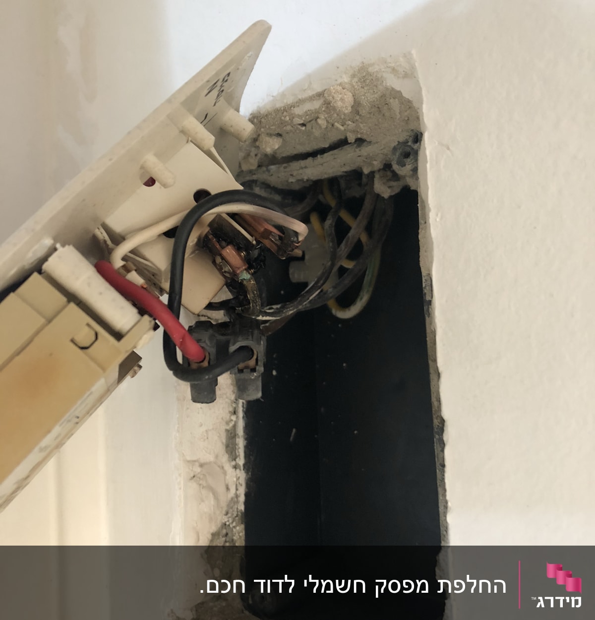 חוטי חשמל חשופים בקופסת חיבורים בקיר